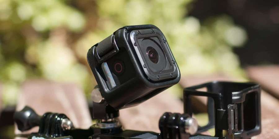 Schwarze Actionkamera auf Stativ im Freien mit grünem Laub im Hintergrund. — Gopro Bilder