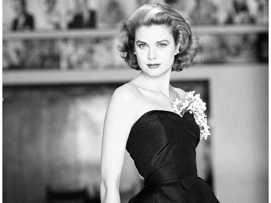 Woman in black strapless gown holding white flowers in studio portrait — Grace Kelly Wallpaper