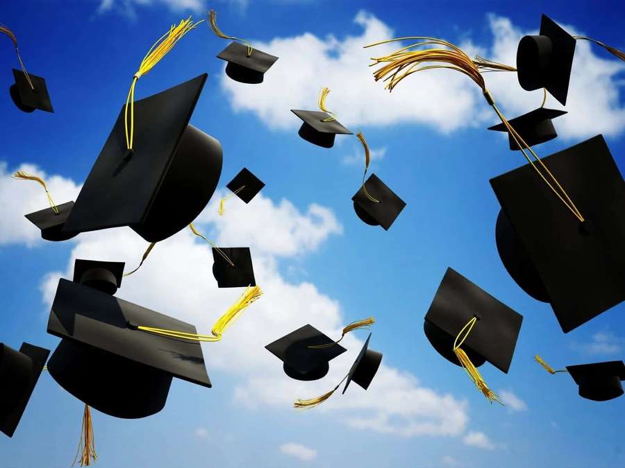 Graduation caps flying in the air against a blue sky with clouds. — Graduation Background