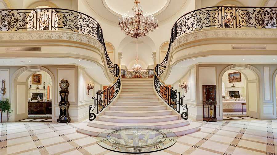 Gran escalera con barandillas de hierro negro en un vestíbulo de una mansión lujosa. — Gran casa Fondos de pantalla