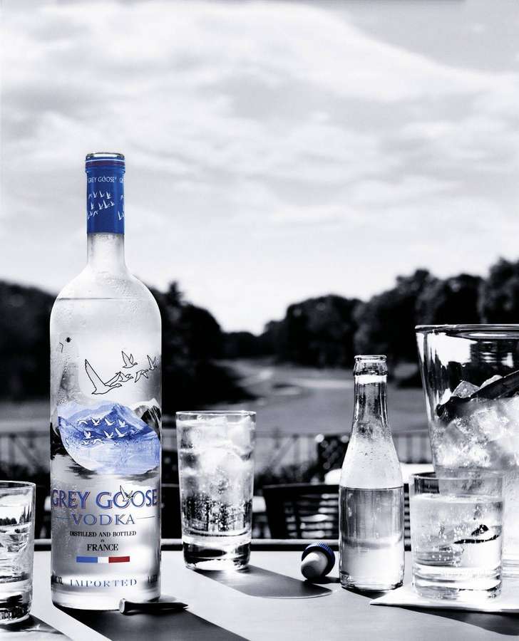 Grey Goose Wodkaflasche und Gläser mit Eis auf einem Tisch im Freien. — Graugans Wallpaper