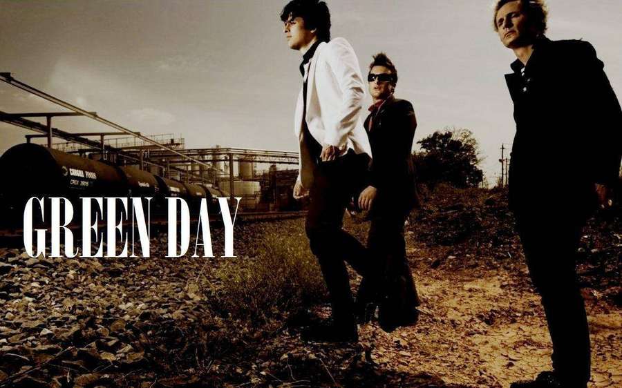 Three men in suits pose near train cars with 'GREEN DAY' text. — Green Day Background