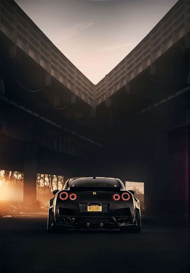 Schwarzer Sportwagen mit roten Rücklichtern, geparkt unter einer Betonbrücke bei Sonnenuntergang. — Gtr iPhone Wallpaper
