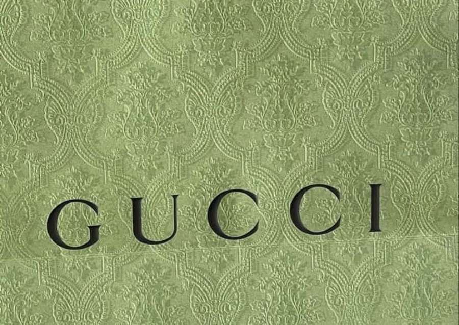Green textured wallpaper featuring the Gucci logo in black. — Gucci Green Wallpaper