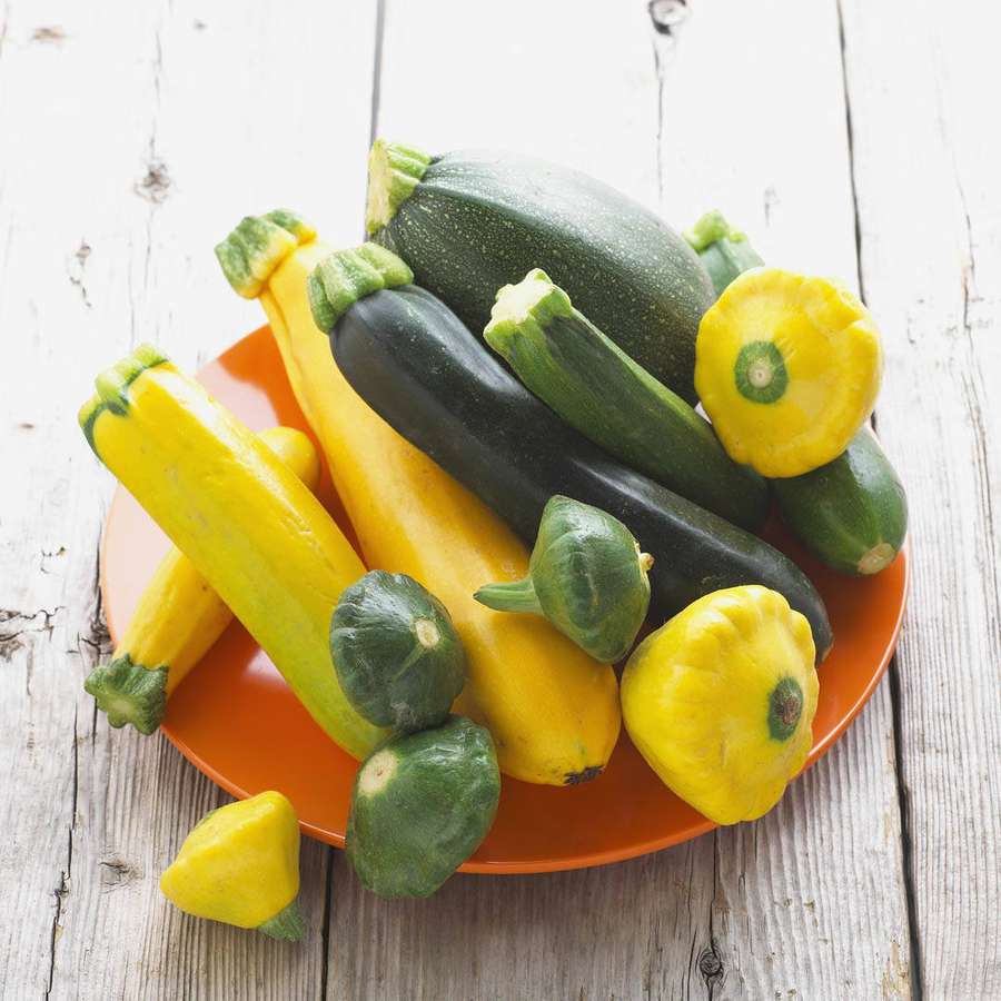 Friske gule og grønne squash og pattypan squash på en oransje tallerken på treoverflate. — Gul Squash Bakgrunner