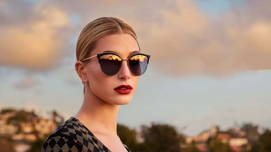 Woman in sunglasses with red lips at sunset overlooking a cityscape. — Hailey Baldwin Wallpaper