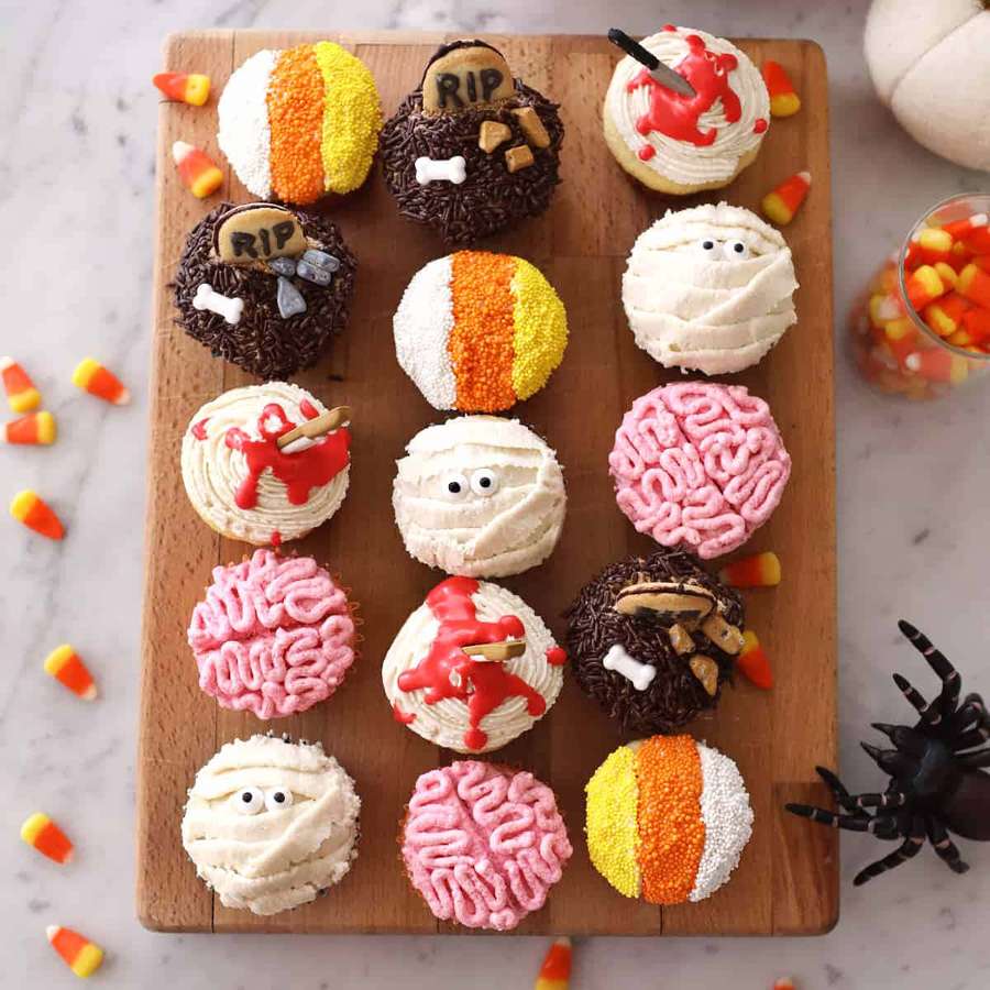 Halloween-kuppikakut muotoiltu muumioiksi, aivoiksi ja hautakiviksi puisella laudalla candy corn -karkkien ja hämähäkin kanssa. — Halloween-muffinit Taustakuvat