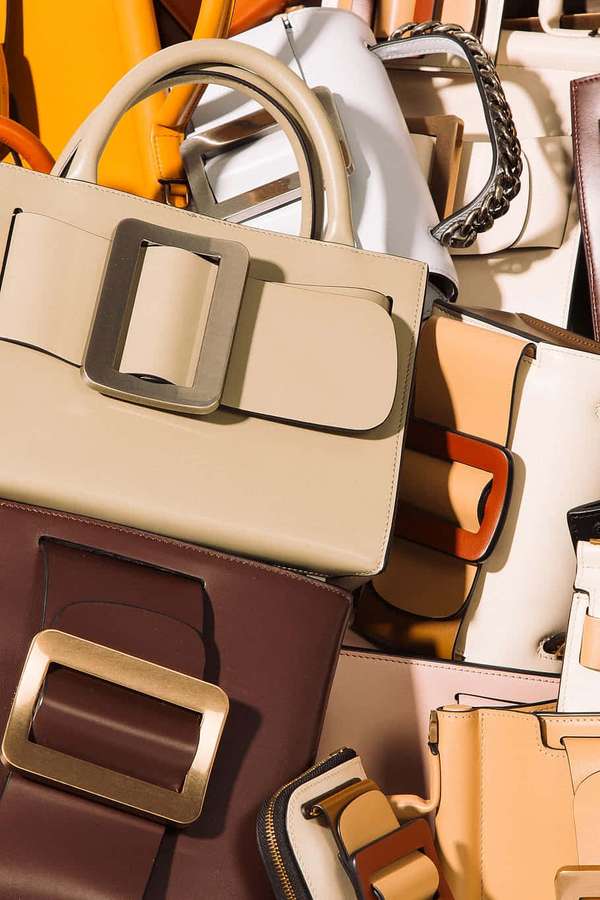 Stacked luxury handbags in beige brown and orange with metallic buckles. — Handbag Background