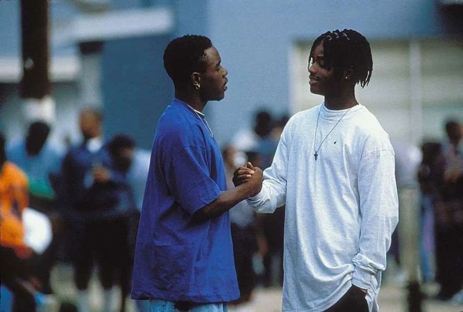 Two young men holding hands and smiling in an urban outdoor setting. — Handshake Background