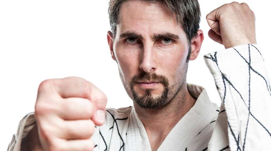 Ein Mann in einer Kampfsportuniform schlägt mit entschlossenem Ausdruck nach vorne. — Hapkido Bilder