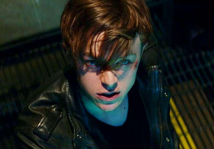 Young man in leather jacket looking up in dark neon-lit alley — Harry Osborn Wallpaper