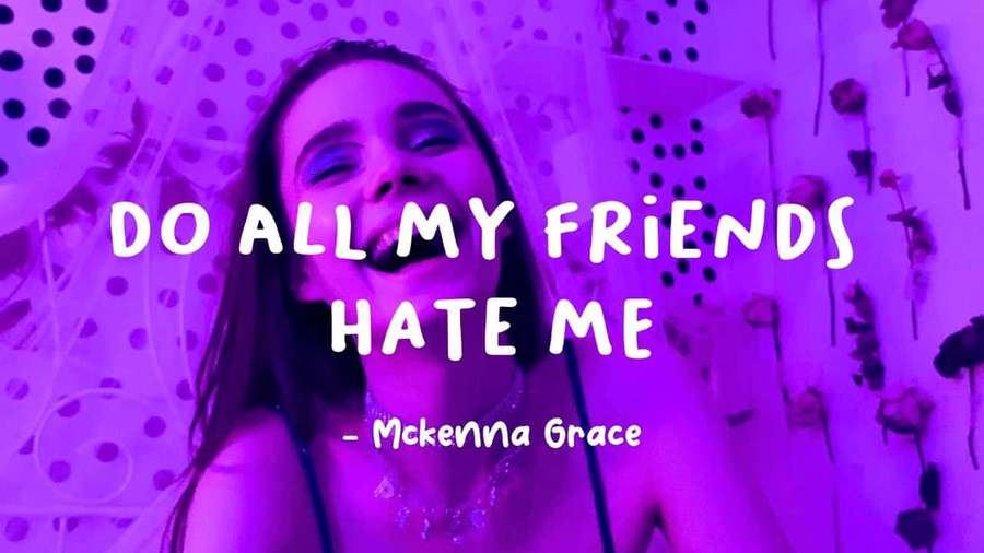 Eine lächelnde Frau mit lila Beleuchtung und Textüberlagerung, die 'DO ALL MY FRIENDS HATE ME' von Mckenna Grace zeigt. — Hasse Mich Wallpaper