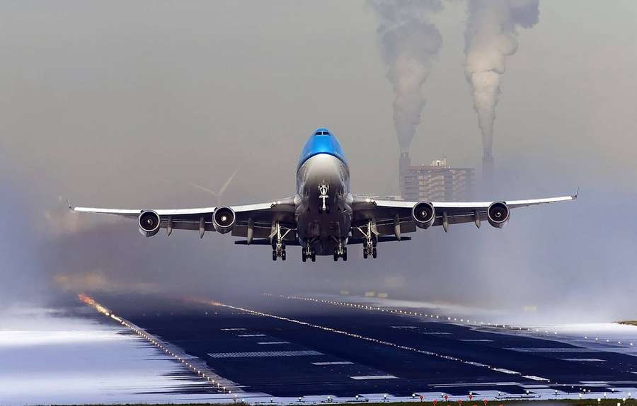 Jumbojet landet auf nasser Landebahn mit Rauch aus Fabriken im Hintergrund — HD flugzeug Wallpaper