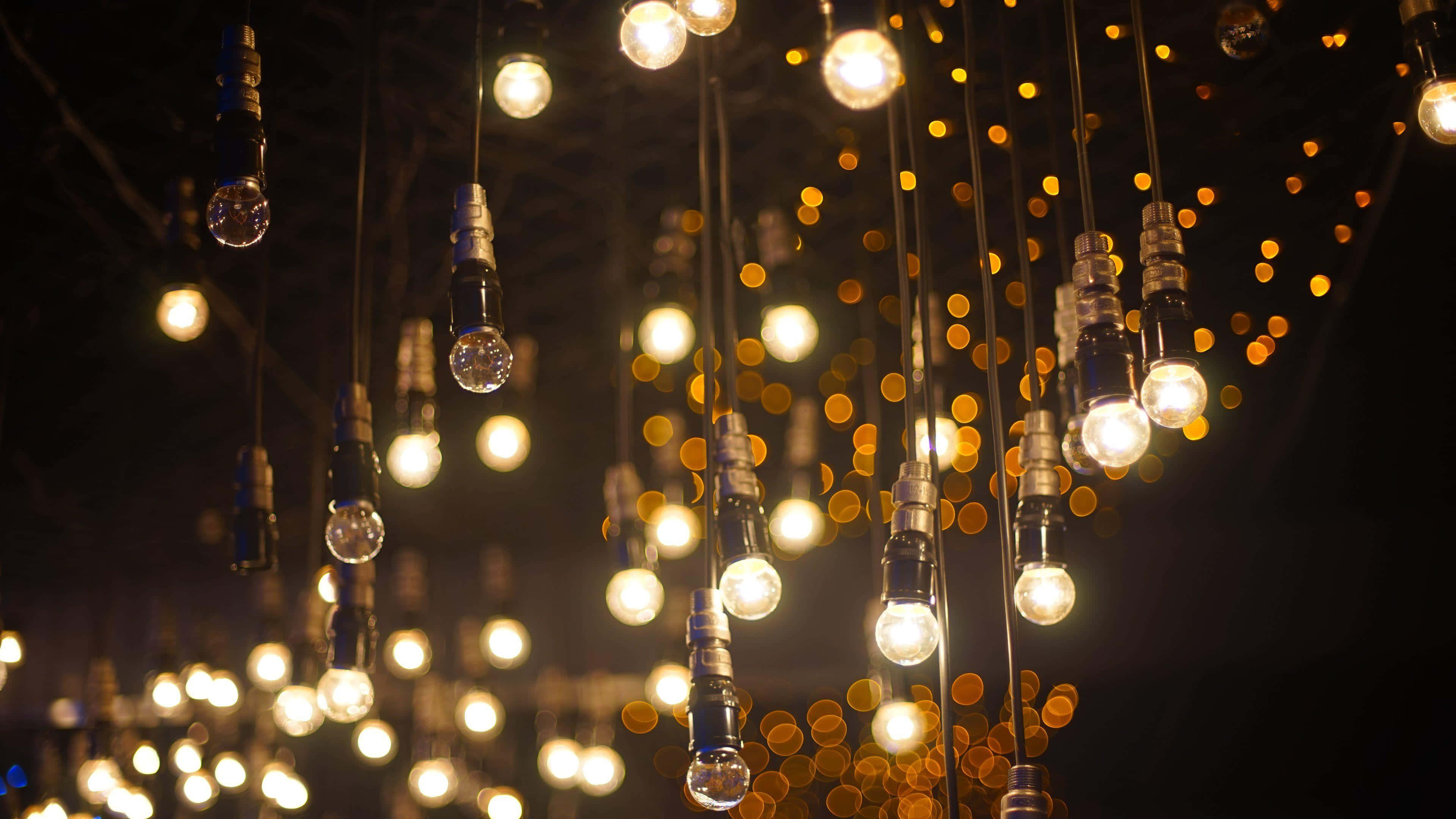 Hanging light bulbs glowing warmly against a dark background with bokeh lights. — HD Light Background