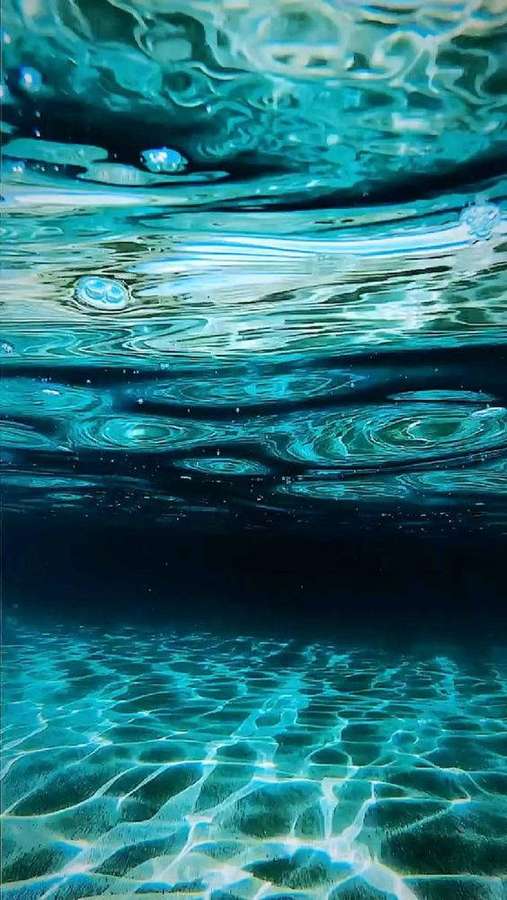 Agua turquesa ondula con patrones de luz y profundidades submarinas oscuras. — Hermoso mar Fondos de pantalla