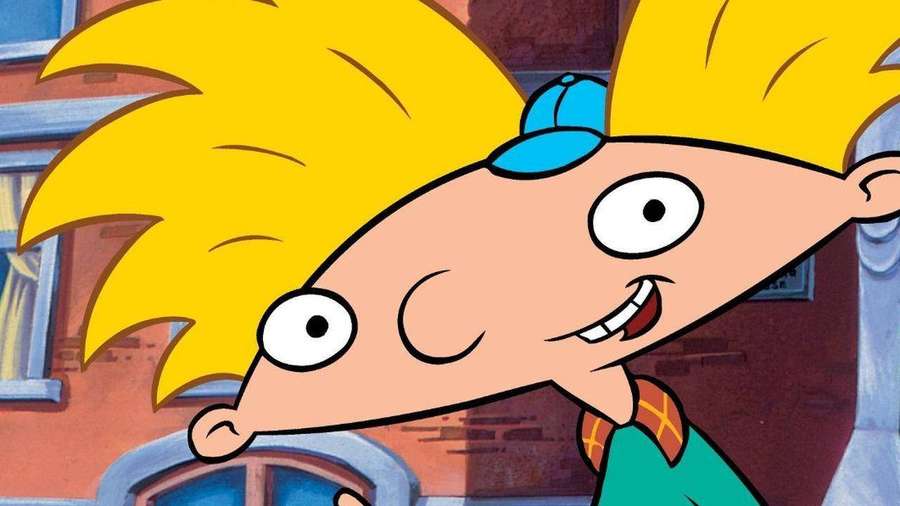 Cartoon boy with spiky yellow hair and blue cap grinning cheerfully. — Hey Arnold Background