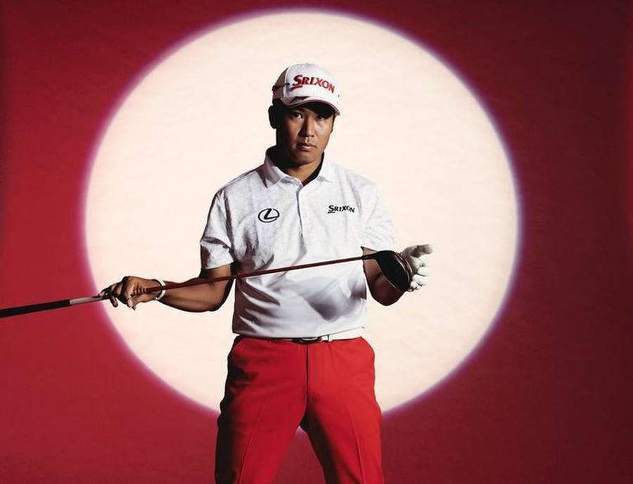 Professional golfer in red pants and white shirt holding a club under a spotlight. — Hideki Matsuyama Wallpaper