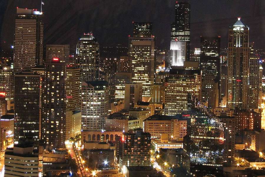 Vista nocturna de un denso horizonte urbano con rascacielos iluminados y calles brillantes. — Horizonte de Seattle Fondos de pantalla