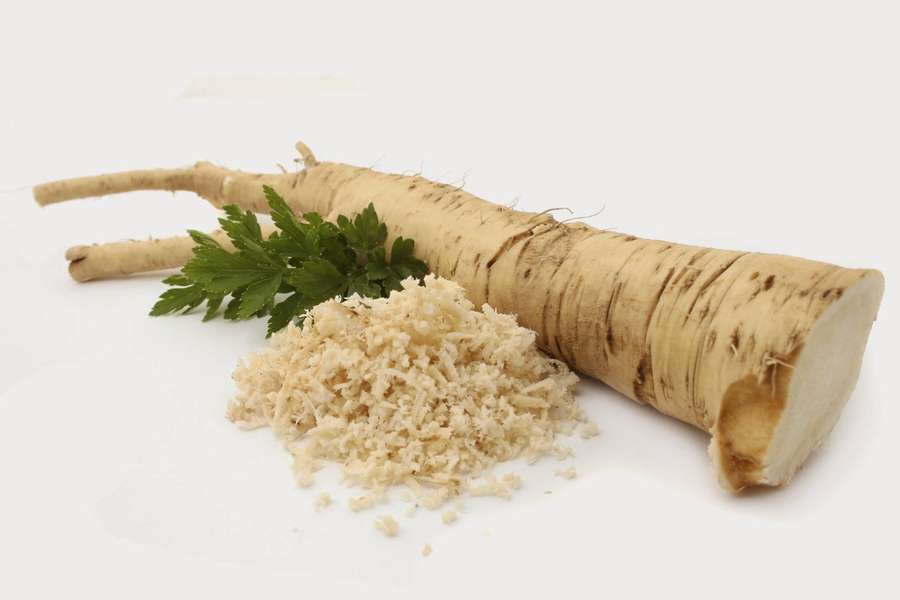 Fresh whole and grated parsnip with green leaves on white background — Horseradish Wallpaper