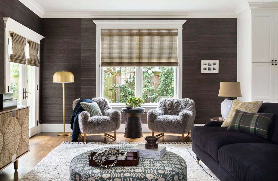 Cozy living room with dark wood walls, fluffy chairs, and patterned ottoman. — House Interior Background