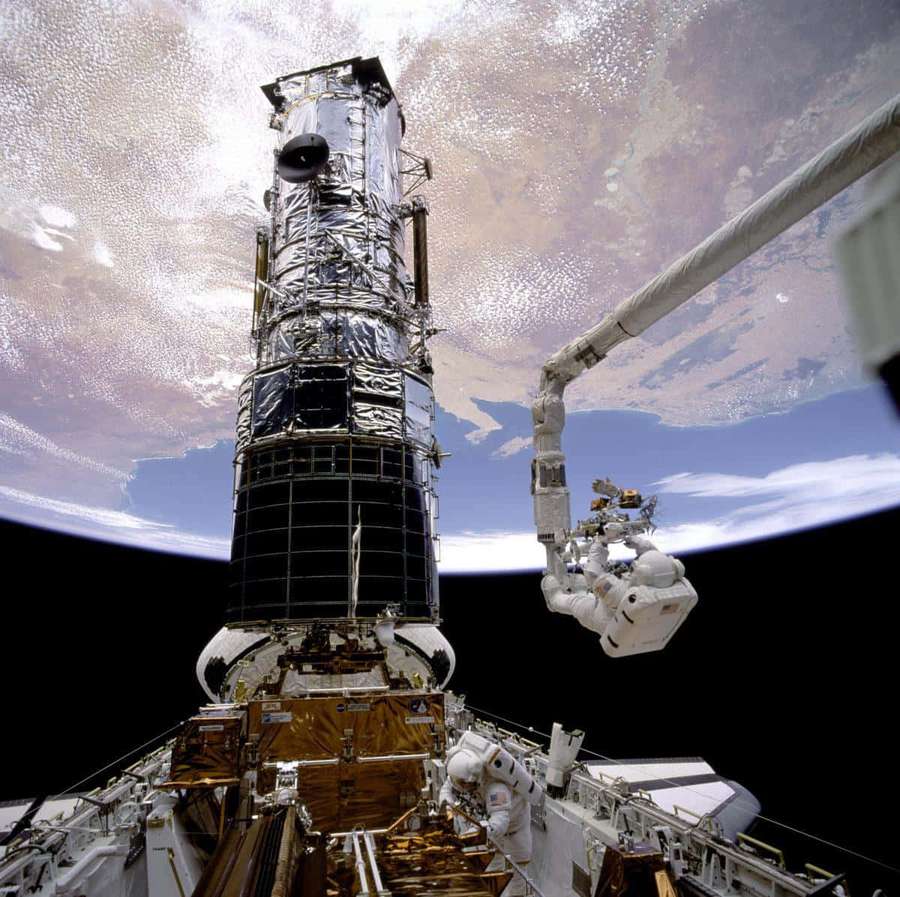 Astronauten warten das Hubble-Weltraumteleskop im Orbit über der Erde. — Hubble Bilder