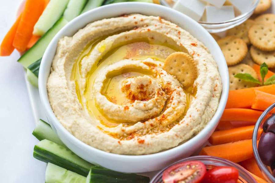 Creamy hummus with olive oil and paprika served with fresh vegetable sticks and crackers. — Hummus Wallpaper