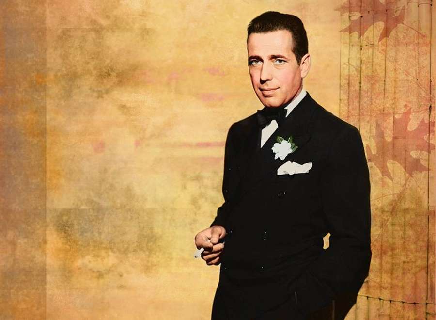 Un uomo in uno smoking nero con un boutonniere di fiori bianchi che tiene una sigaretta. — Humphrey Bogart Sfondi