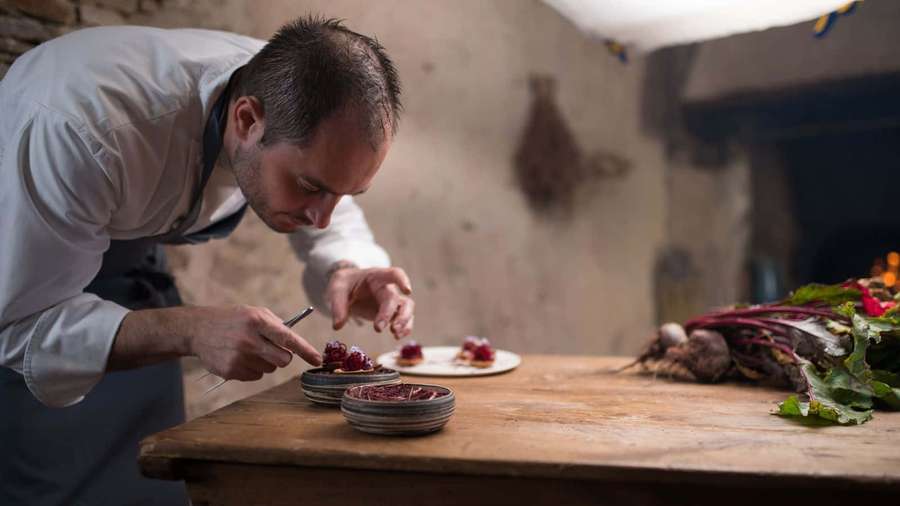 Chef adornando platos de remolacha en cocina rústica de piedra — Imágenes de Chef Imágenes