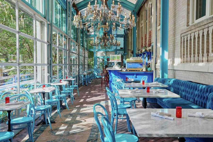 Comedor turquesa con mesas de mármol y lámparas de araña bañado en luz solar. — Imágenes de San Antonio Imágenes