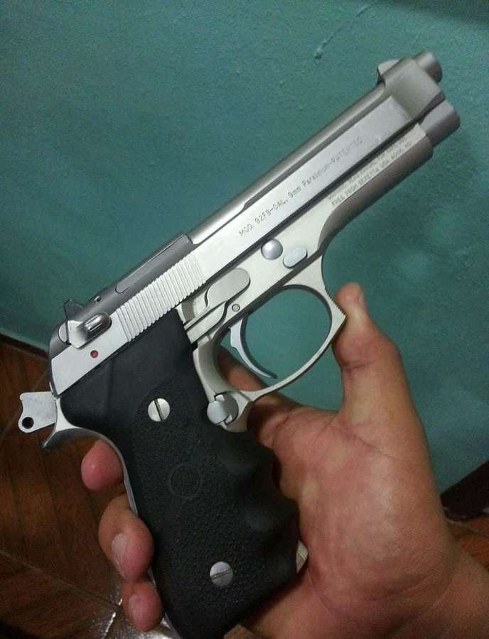 Mão segurando uma pistola prateada e preta em ambiente interno. — Imagens de pistol Fotos