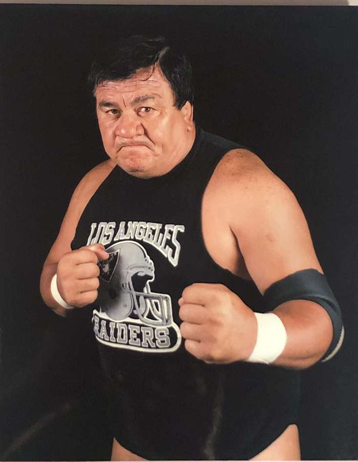 Wrestler in schwarzem Los Angeles Raiders Tanktop mit weißen Armbandagen, der mit geballten Fäusten posiert. — Indianer Wallpaper