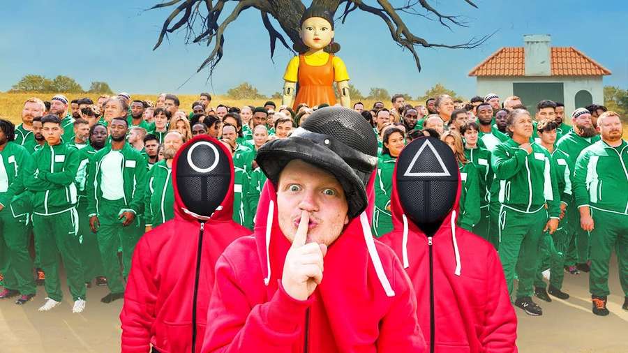 Hombre con sudadera roja sosteniendo el dedo en los labios frente a una multitud con chándales verdes con muñeco en el árbol. — Inefable Fondos de pantalla