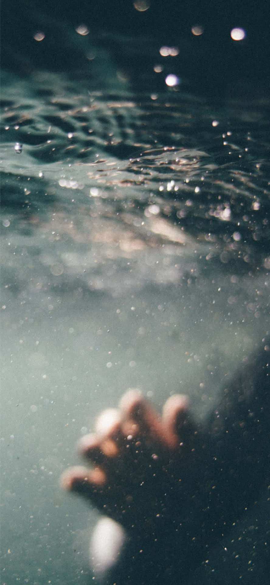 Tangan meraih ke atas dari bawah air dengan gelembung dan cahaya yang menyaring. — Ini Wallpaper