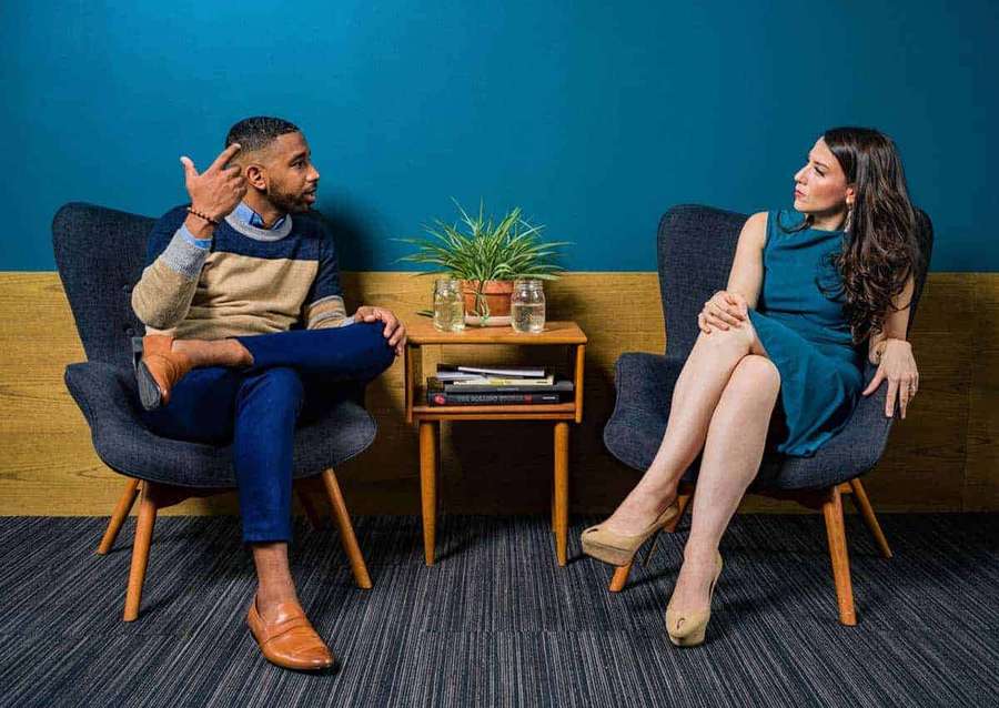 Two people in chairs having a conversation indoors. — Interview Picture