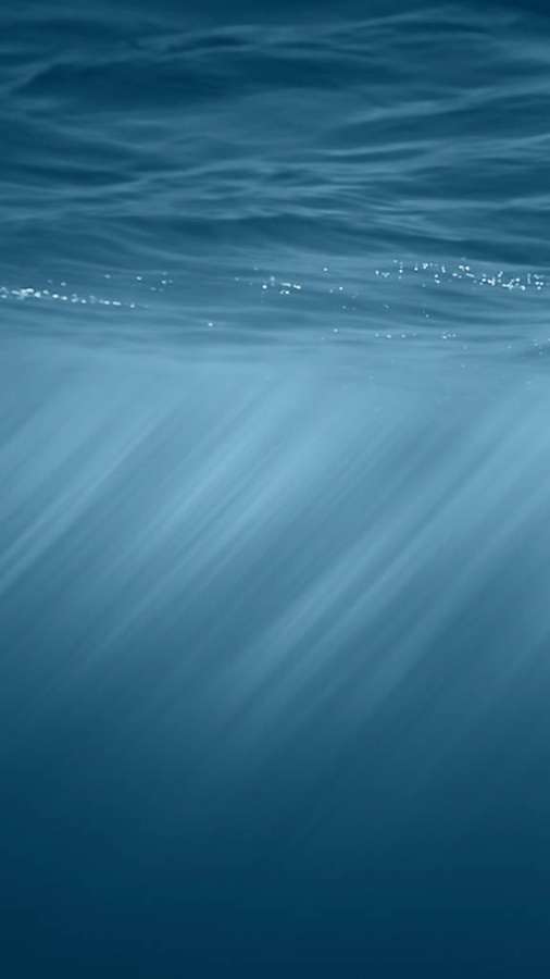 Sonnenstrahlen scheinen durch die Meeresoberfläche unter Wasser in Blautönen. — iOS Bilder