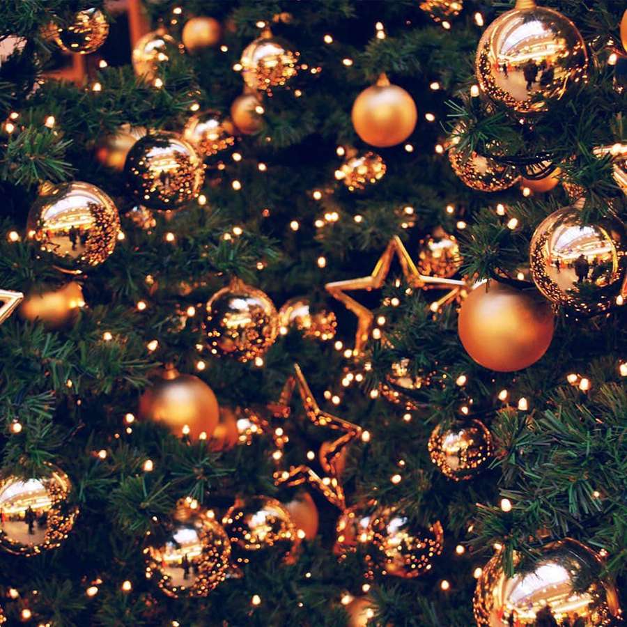 Close-up of a decorated Christmas tree with gold ornaments and lights. — iPad Christmas Background