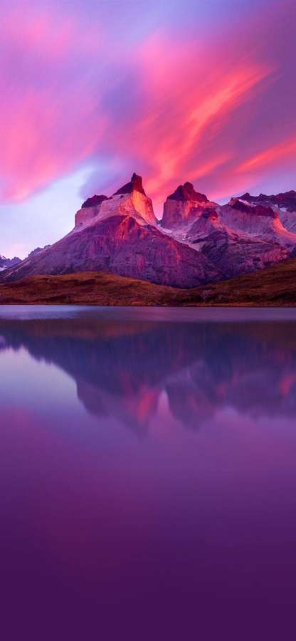 Montagne rosa e viola riflesse in un lago calmo al tramonto. — iPhone Xr Sfondi