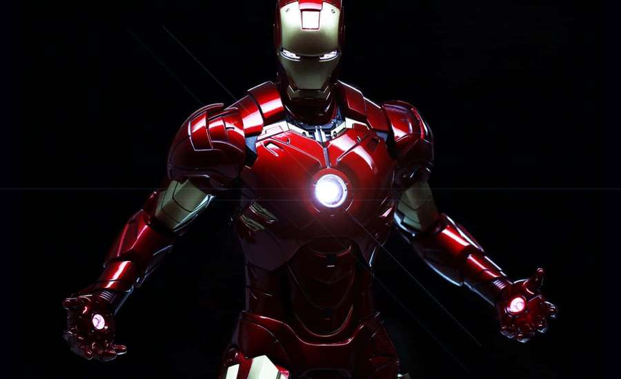 Iron Man in red and gold armor with glowing chest and repulsors against black background — Iron Man Background