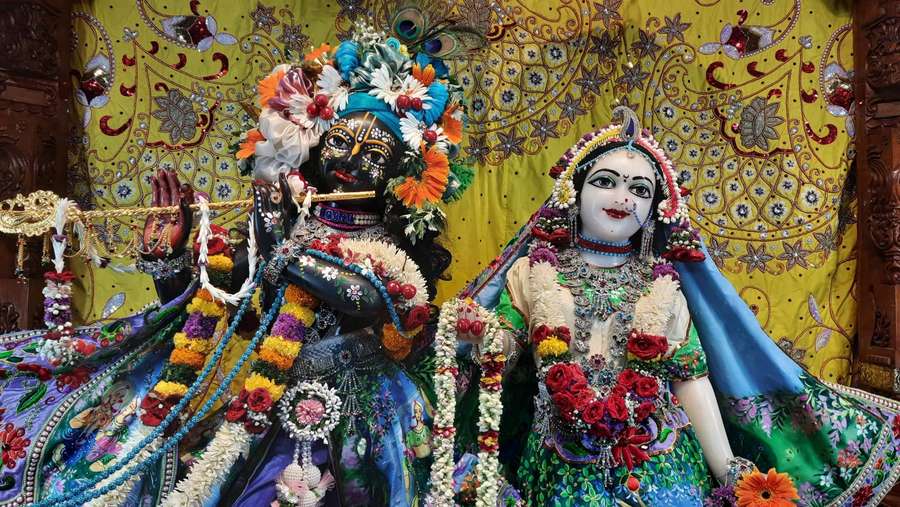 Zwei geschmückte hinduistische Gottheiten sitzen gemeinsam in einer Tempelumgebung. — Iskcon Bilder