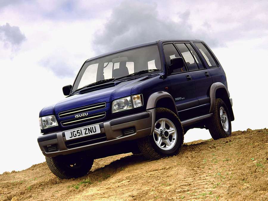 Blue Isuzu Trooper SUV driving up a dirt hill under cloudy skies. — Isuzu Ascender Wallpaper