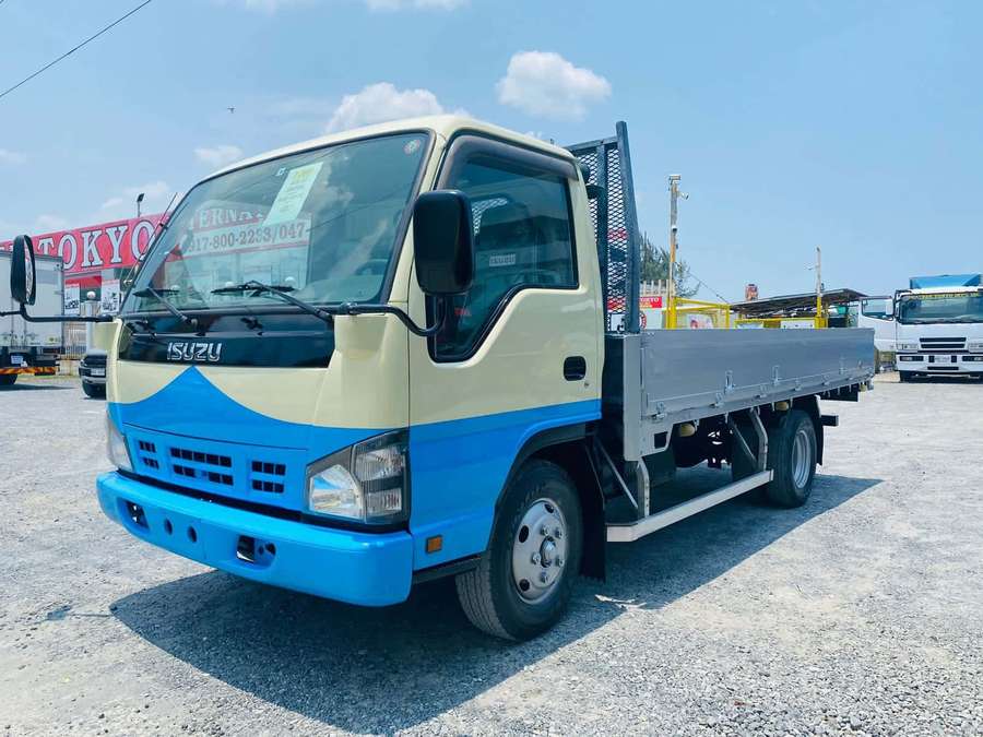 Blauer und cremefarbener Isuzu Pritschenwagen auf Kiesplatz — Isuzu Elf Wallpaper