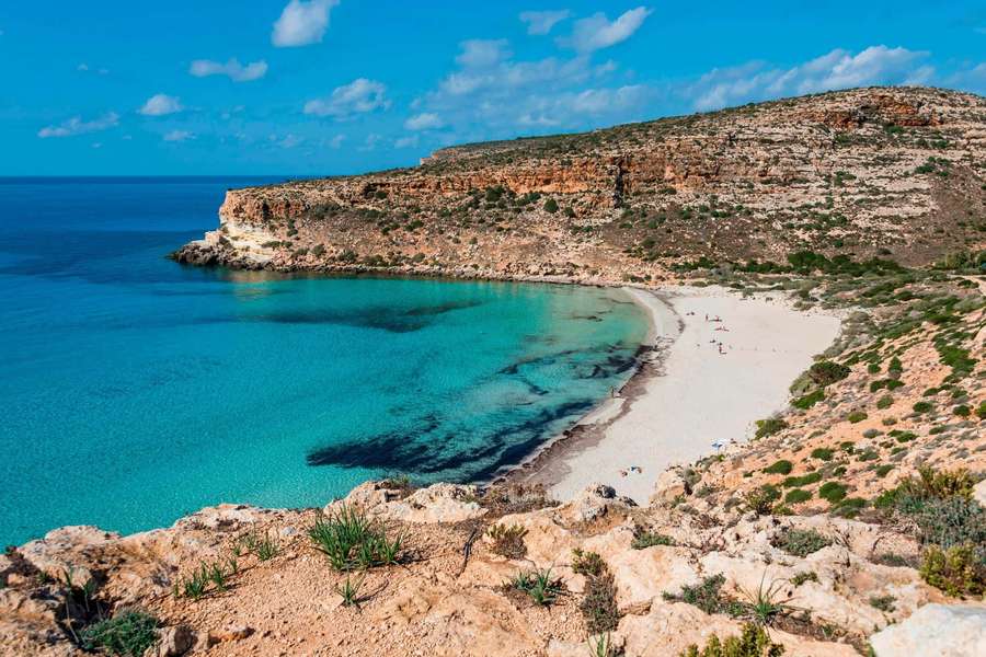 Turquoise cove with white sand beach surrounded by rocky cliffs under a clear blue sky. — Italian Beach Wallpaper