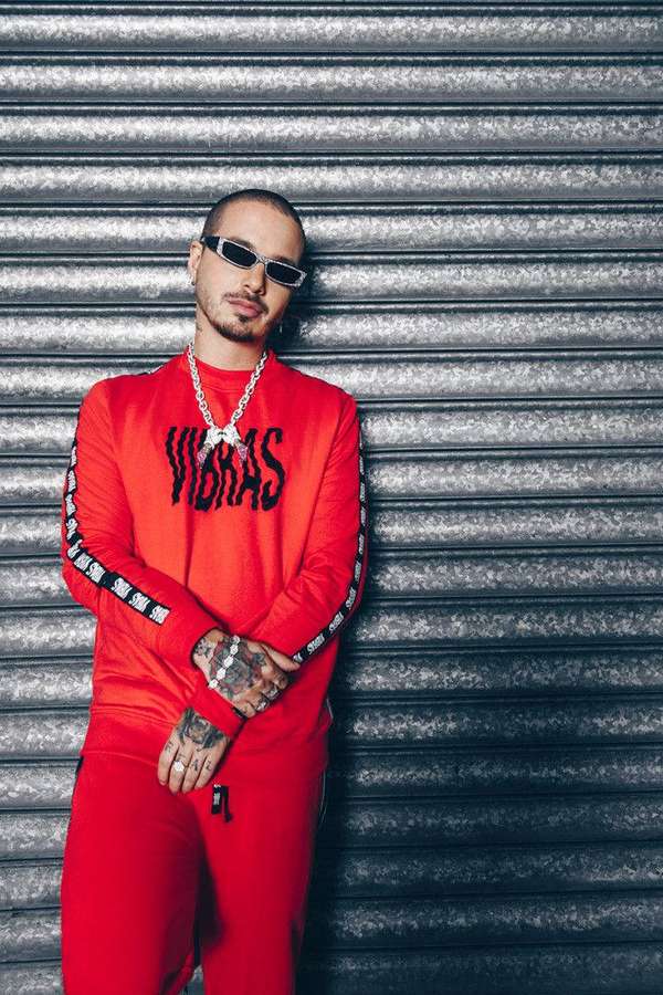Man in red tracksuit and sunglasses leaning against metal shutter. — J Background