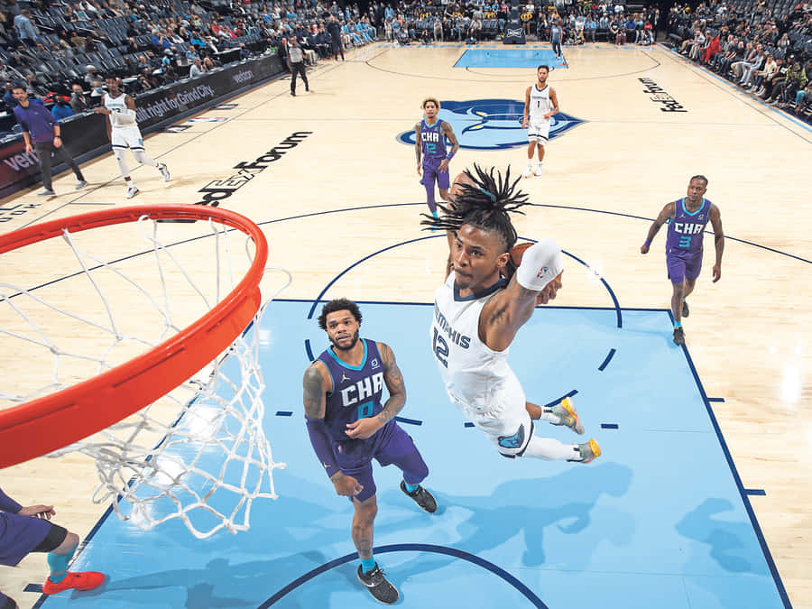 Basketball player mid-air dunking over defender in arena. — Ja Morant Dunk Wallpaper