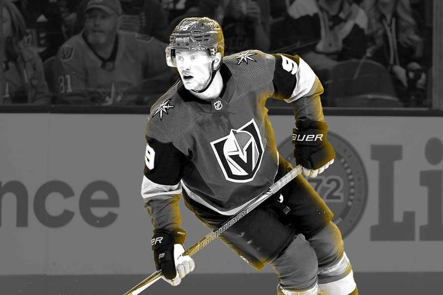 Hockey player in Vegas Golden Knights jersey skating during a game with crowd in background. — Jack Eichel Background