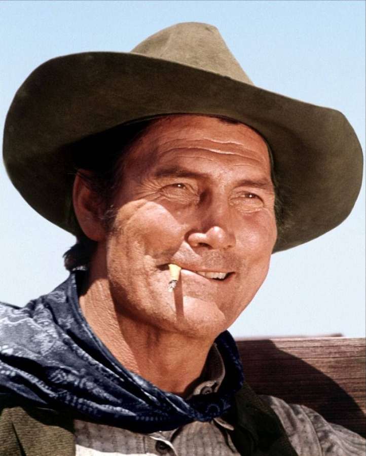 Un cowboy sorridente con cappello e sigaretta in bocca sotto il sole splendente. — Jack Palance Sfondi