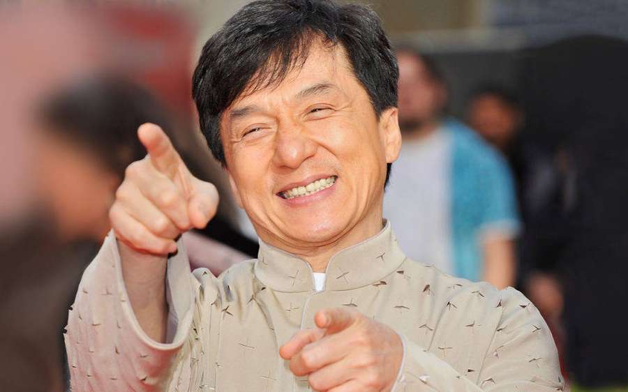 Jackie Chan smiling and pointing at the camera at an event. — Jackie chan Wallpaper