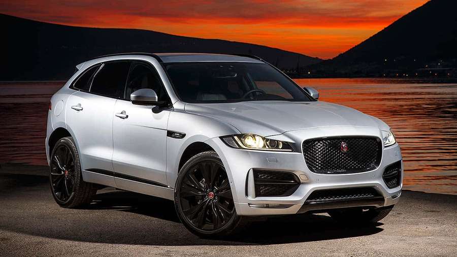 Silver Jaguar F-Pace SUV parked by lake at sunset with orange sky and dark hills. — Jaguar F-pace Wallpaper