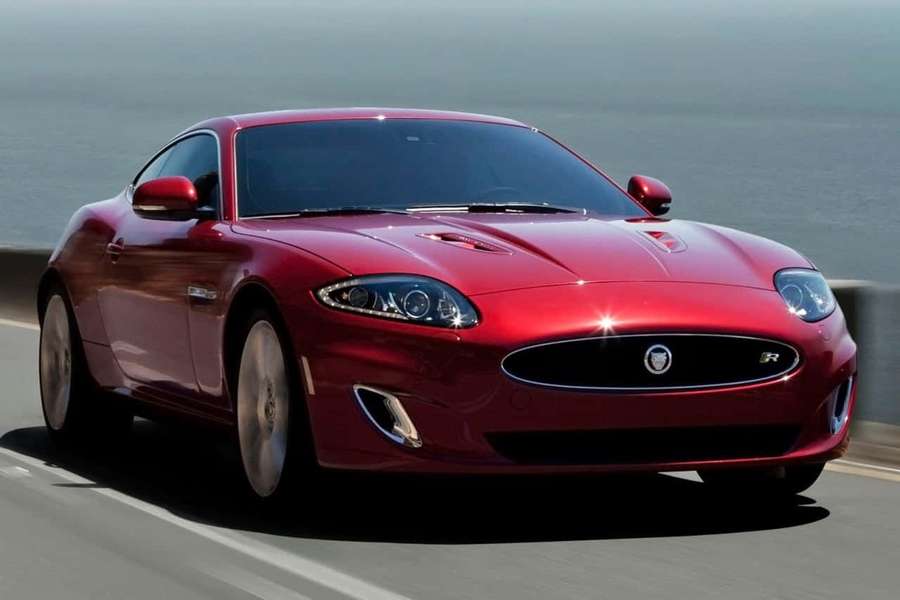 Red Jaguar sports car driving on coastal highway near ocean. — Jaguar Xkr Wallpaper