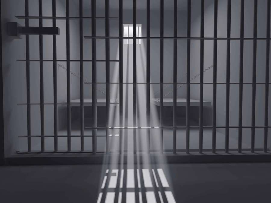 Prison cell with metal bars and a single beam of light shining through a high window. — Jail Cell Background